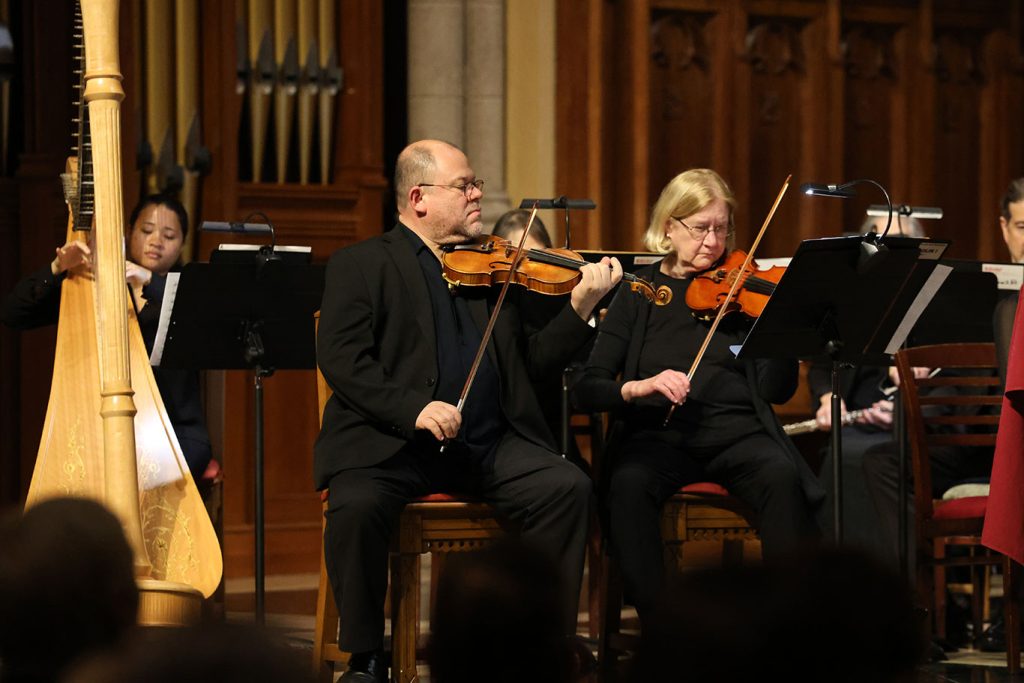 Two violinists sitting on stage at the University Church