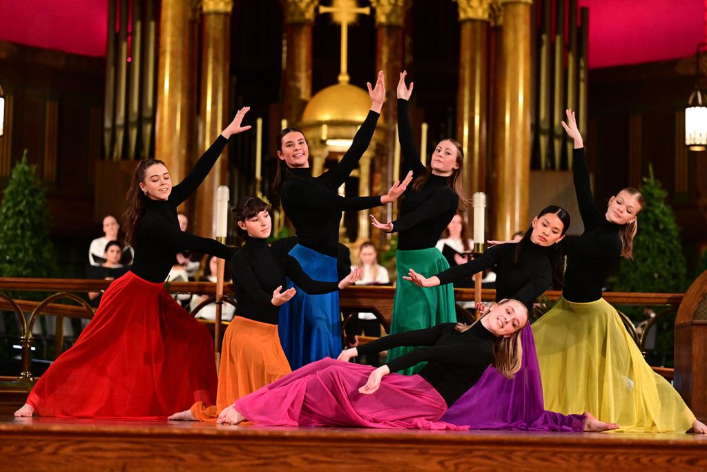 dancers pose together with their hands raised in the air