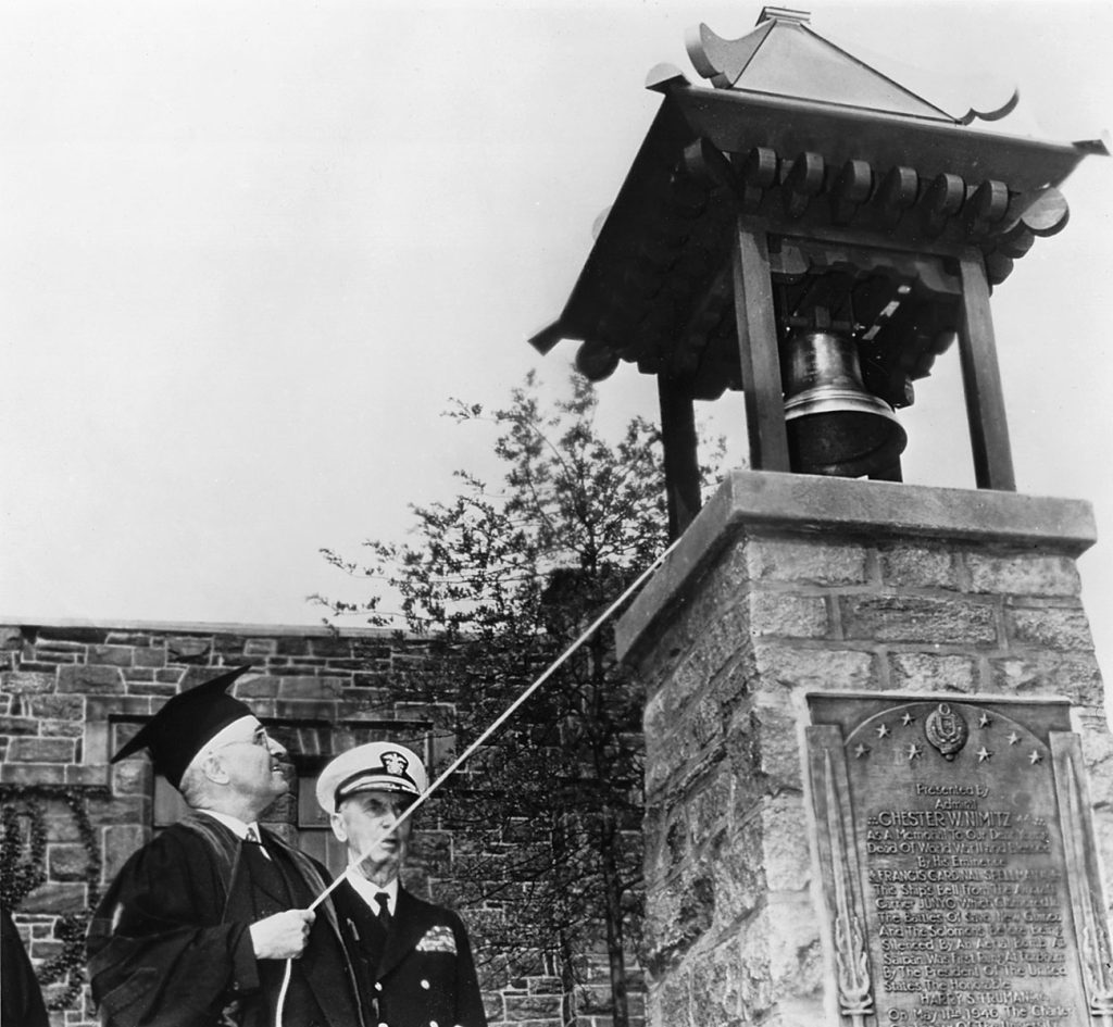 President Harry S. Truman rings the Fordham Victory Bell on May 11, 1946. Standing alongside Fleet Admiral Chester W. Nimitz, he becomes the first to ring the bell newly installed outside the Rose Hill Gym.