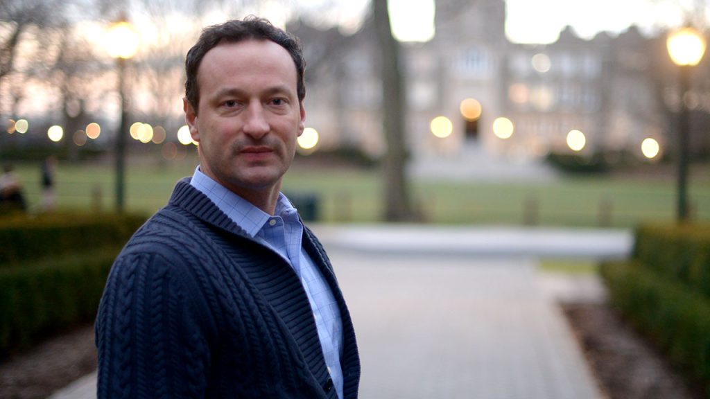 A man facing the camera with Keating Hall behind him