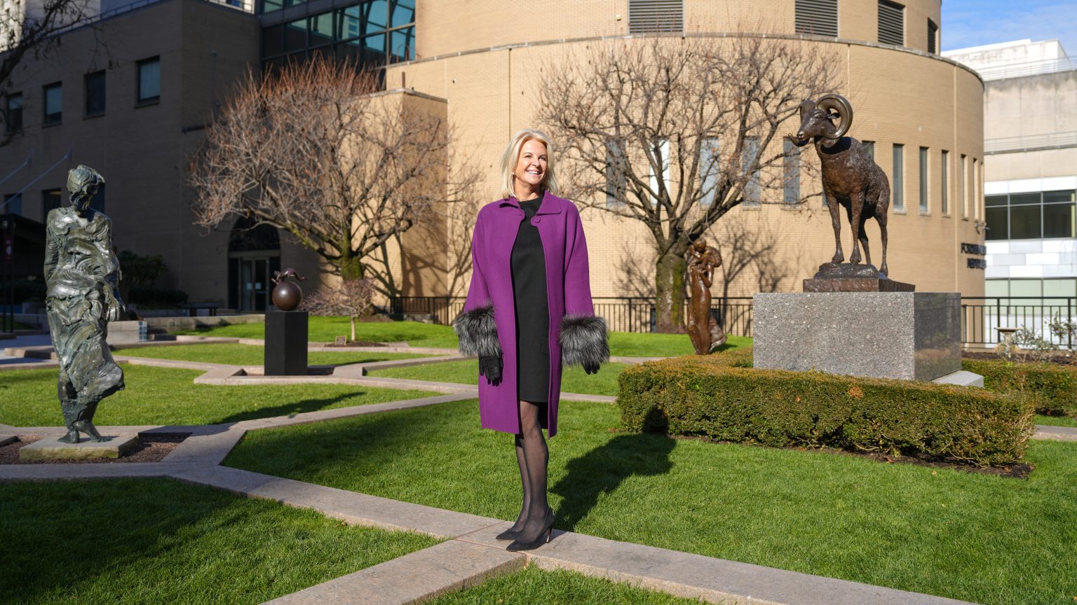 Fordham Trustee Kim Bepler stands on campus surrounded by sculptures.