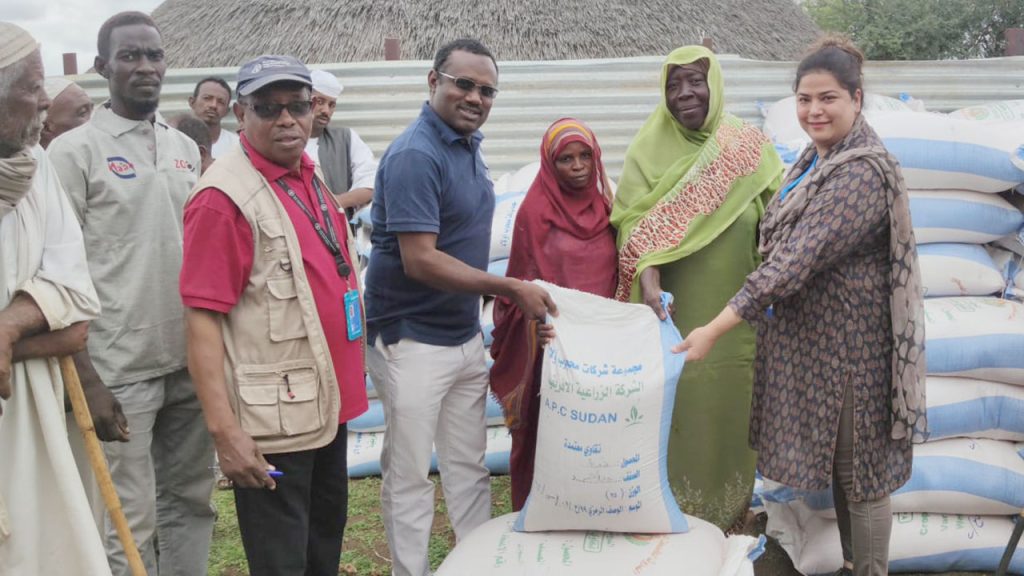 People gathered around a bag of rice.