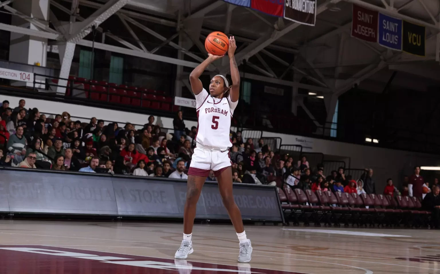 A woman basketball player shooting a basketball.