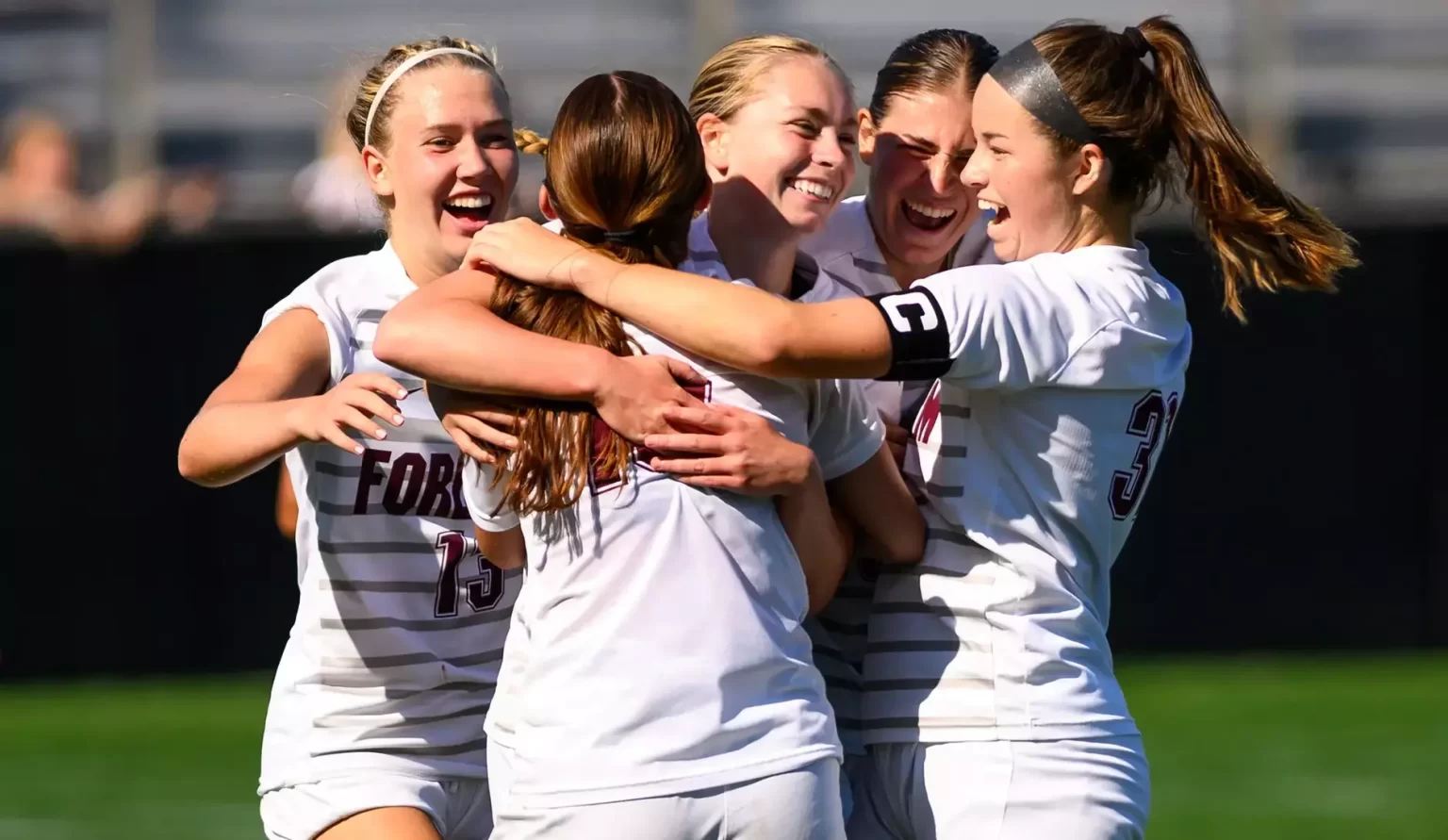 5 players hugging and cheering on field