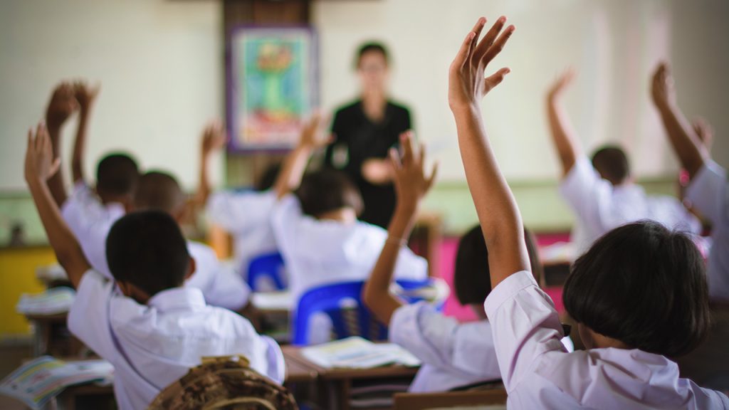 Classroom with many hands raised