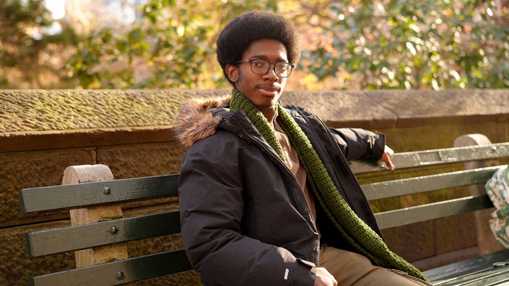 A man sitting on a bench with his arm extended.