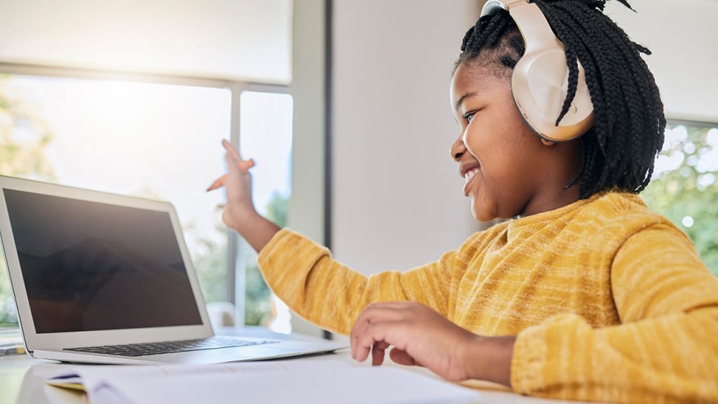 A child sitting in front of a computer with headphones on.